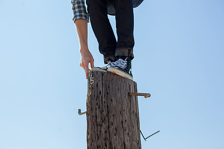 person standing on brown wooden pole during daytime thumbnail