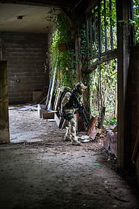 armored man carrying black rifle looking outside thumbnail