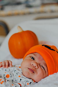 selective focus photography of baby in orange cap lying on bed thumbnail