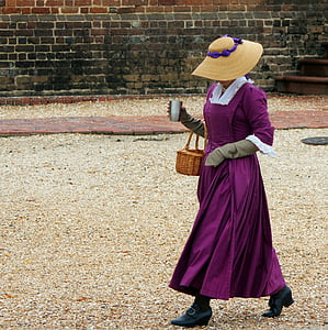 woman walking while holding basket and cup near wall thumbnail