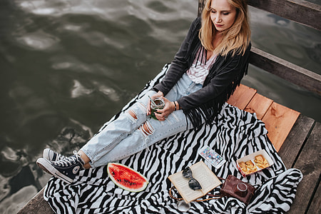 Blonde woman having a healthy snack at the wooden pier thumbnail