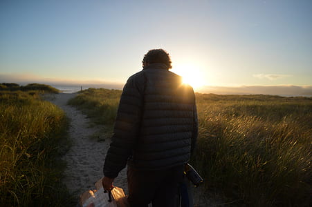 man walking on sand path during daytime thumbnail