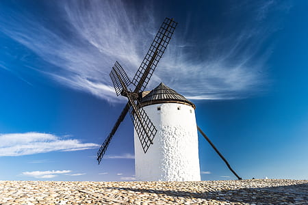 white lighthouse with black windmill under white clouds photography thumbnail