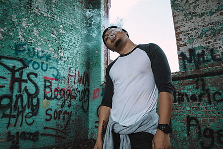 man standing on teal graffiti wall thumbnail