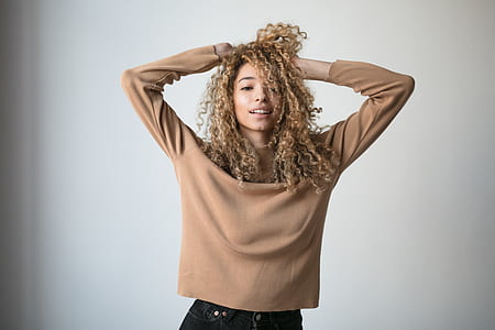 woman wearing brown sweater standing near white painted wall thumbnail