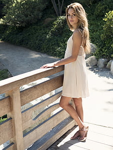 woman wearing white sleeveless dress on brown wooden bridge during daytime thumbnail