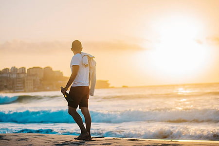 man wears white shirt on gray sand during sunsety thumbnail
