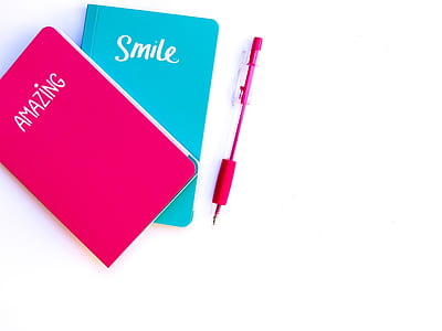 pink and blue books near pink click pen thumbnail