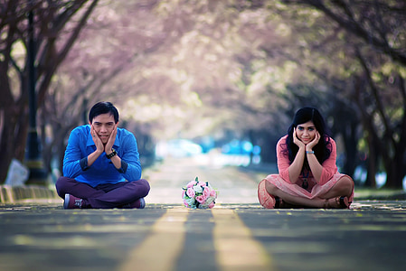 man and woman sitting on gray asphalt road under trees during daytime thumbnail