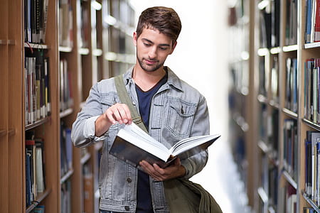 man holding a book inside library thumbnail