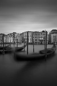 grayscale photo of buildings beside body of water with gondolas thumbnail