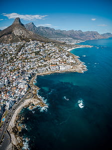 aerial photography of houses near body of water and mountains at daytime thumbnail