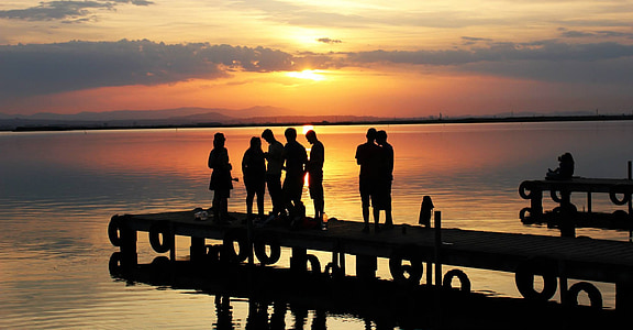 seven silhouette of person on sea dock at sunset thumbnail