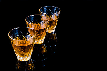 three clear shot glasses on black surface thumbnail