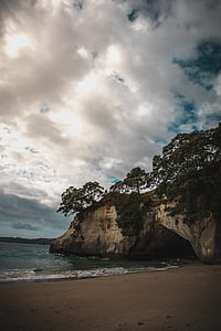 seashore near rock boulder under cloudy sky thumbnail