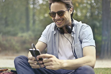 Young Man Wearing Sunglasses And Listening To Music With His Smartphone thumbnail