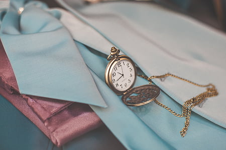 round brass-colored analog pocket watch on blue textile thumbnail