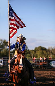photo of woman riding on horse and holding flag thumbnail