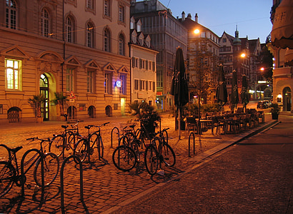 gray bicycles park near green patio umbrella during nighttime thumbnail