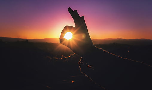 silhouette photo of okay hand sign through sunrise thumbnail