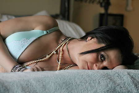 woman lying of bed with gray bed sheet wearing teal brassiere during daytime thumbnail