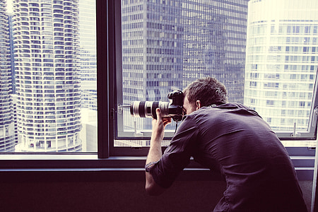 man wearing black dress shirt taking photo in building inside room thumbnail