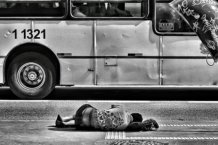 grayscale photo of person lying on road beside bus thumbnail
