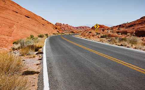 gray asphalt road between of desert during daytime thumbnail