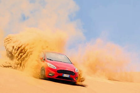 Red Ford Focus Vehicle Driving on Sand Under Blue Daytime Sky thumbnail