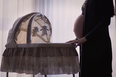 woman in black cardigan in front of white bassinet thumbnail