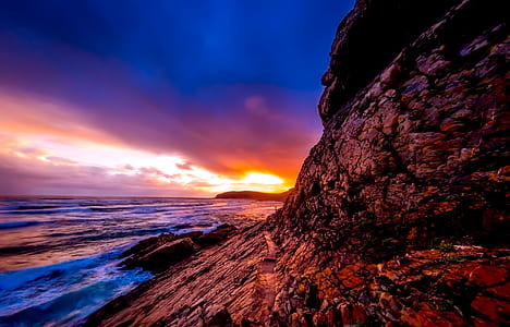 brown rocky mountains beside sea during sunset thumbnail