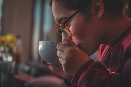 selective focus photography of woman drinking from teacup thumbnail