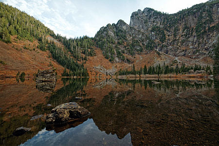 landscape photo of body of water near mountain at daytime thumbnail