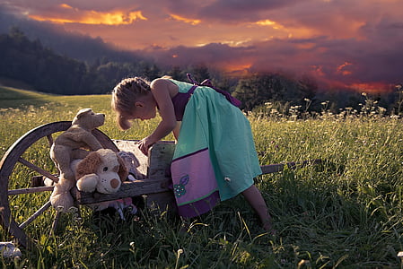 girl playing on green grass during daytime thumbnail