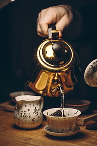 person holding brass kettle under white teacup on white saucer thumbnail