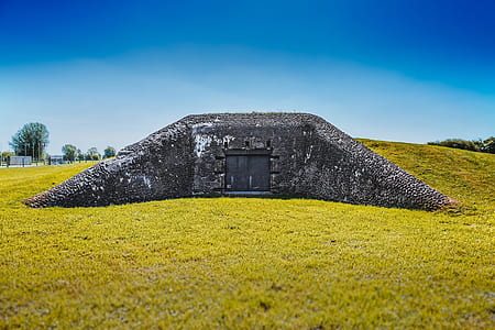 black concrete wall surrounded by green grass field under blue sky at daytime thumbnail