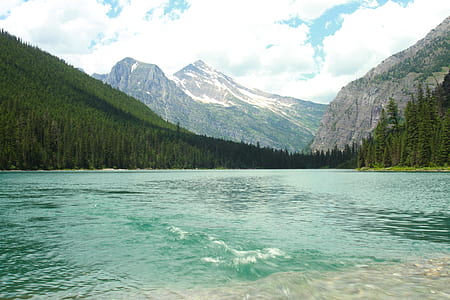 green body of water surrounded with mountains and trees thumbnail
