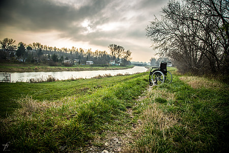 black wheelchair on grass field near river thumbnail