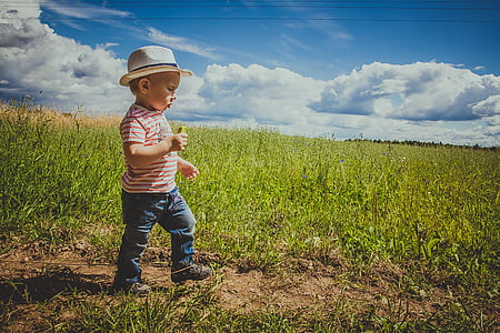 boy standing in middle of grassland under clear sky during daytime thumbnail