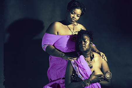 two women in purple clothes standing near wall thumbnail