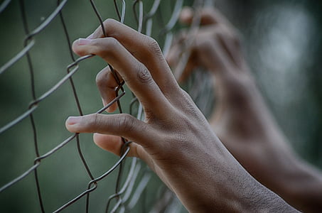 person hands on gray metal fence thumbnail