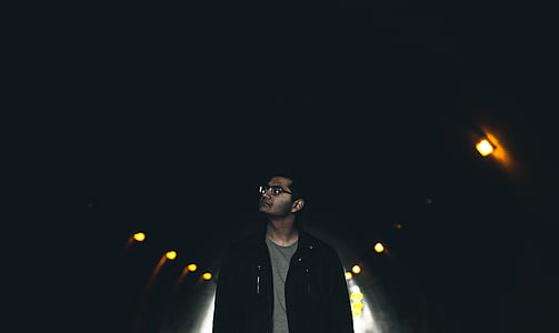 man in black jacket wearing eyeglasses standing near brown sconce thumbnail