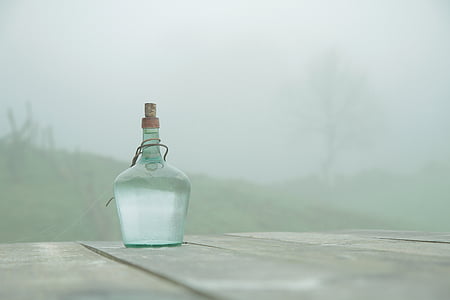 clear glass bottle on gray wooden table thumbnail