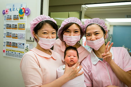three women wearing pink masks and baby posting for photo thumbnail