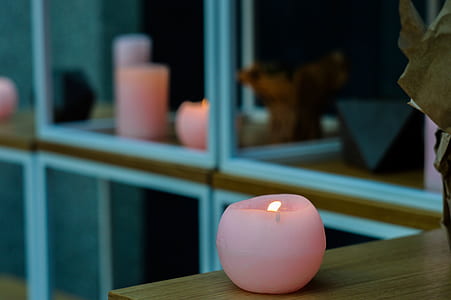 round pink candle on top of brown wooden table thumbnail