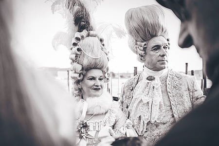 man and woman wearing gray floral dresses in front of man in black top thumbnail