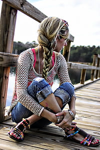 woman wearing white mesh long-sleeved top sitting down and crossing legs on bridge above body of water thumbnail