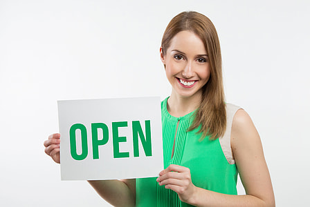 Woman in green and white sleeveless shirt holding white and green card with open text thumbnail