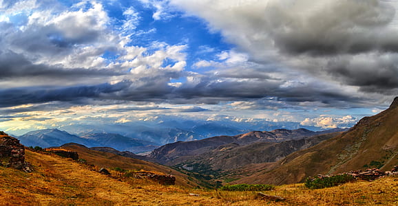 brown mountains under cloudy sky during daytime thumbnail