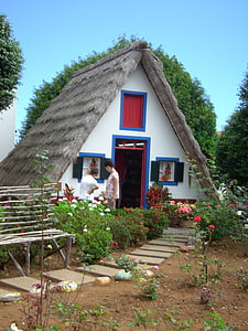 white house with nipa roof and two people standing outside thumbnail